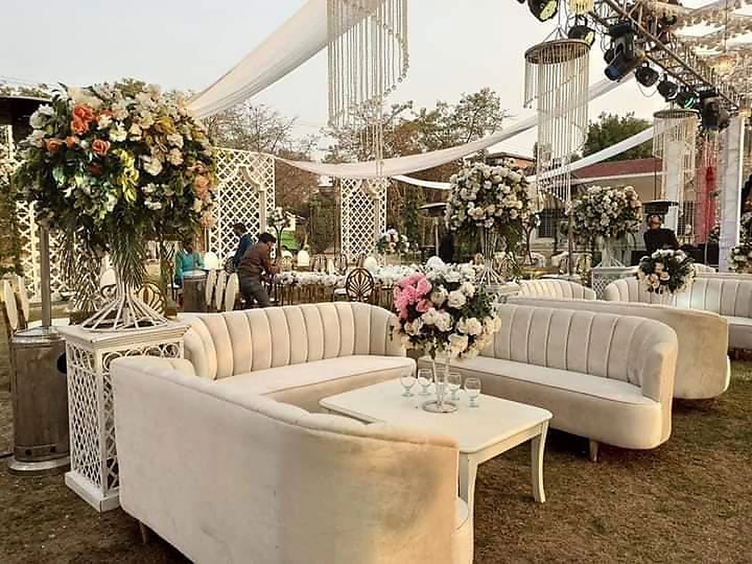 Ivory lounge sofas with marble tables and floral arrangements under a marquee